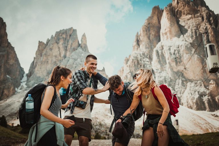 A group of friends laughing while in front of a scenic mountain range