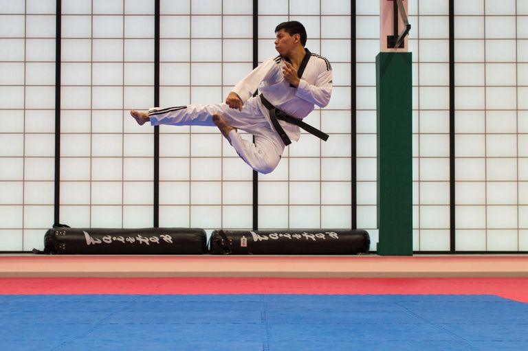 A man doing a flying karate kick in his dojo