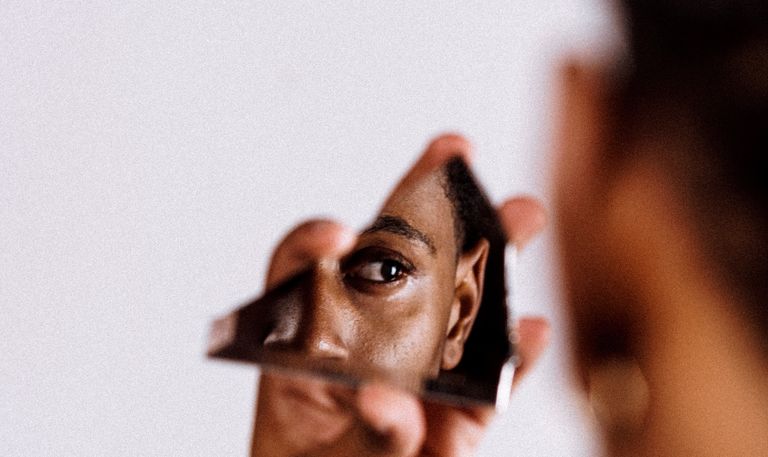 A woman looking at herself in a broken piece of mirror