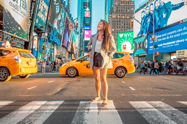 A woman standing in time square new york city in the middle of the intersection